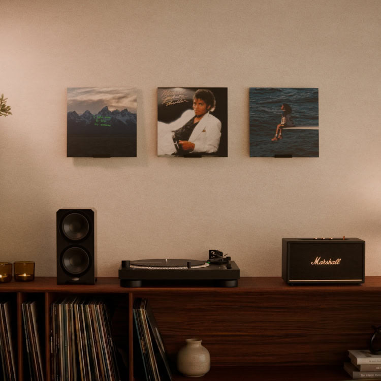 Drie zwarte metalen LP houders van 8 cm met elk één lp boven een platenspeler en speakers (1)