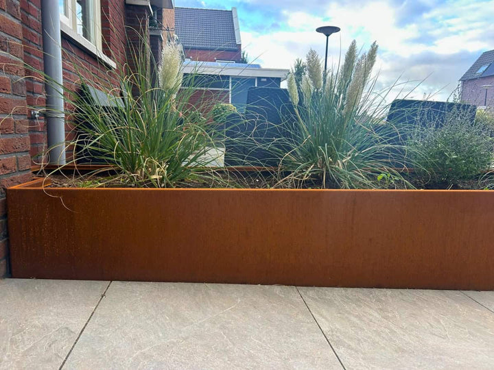 Oplopende cortenstalen plantenbak als hoogteaccent in de tuin