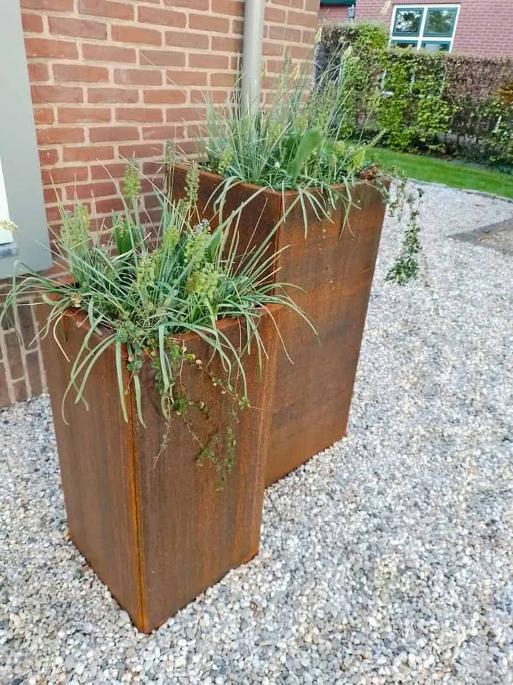 Staande cortenstalen plantenbakken in een tuinopstelling