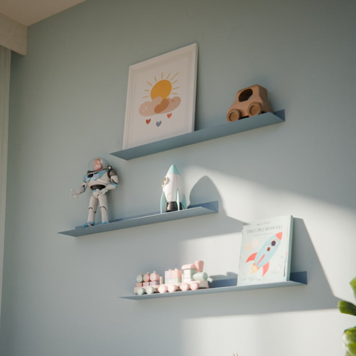 Blauwe metalen wandplank in een babykamer aan de muur gemonteerd