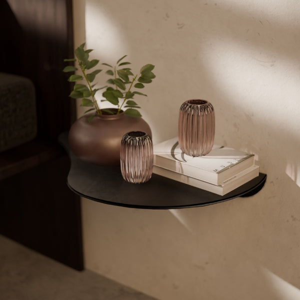 Metalen wandplank als nachtkastje aan de muur gemonteerd naast het bed