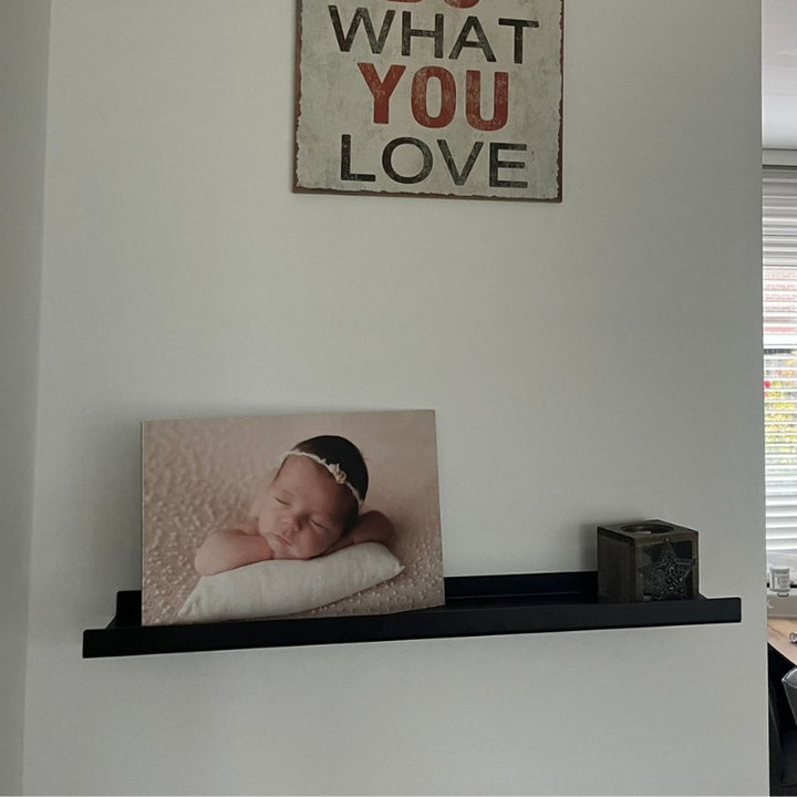 Metalen wandplank voor fotolijsten aan de muur gemonteerd